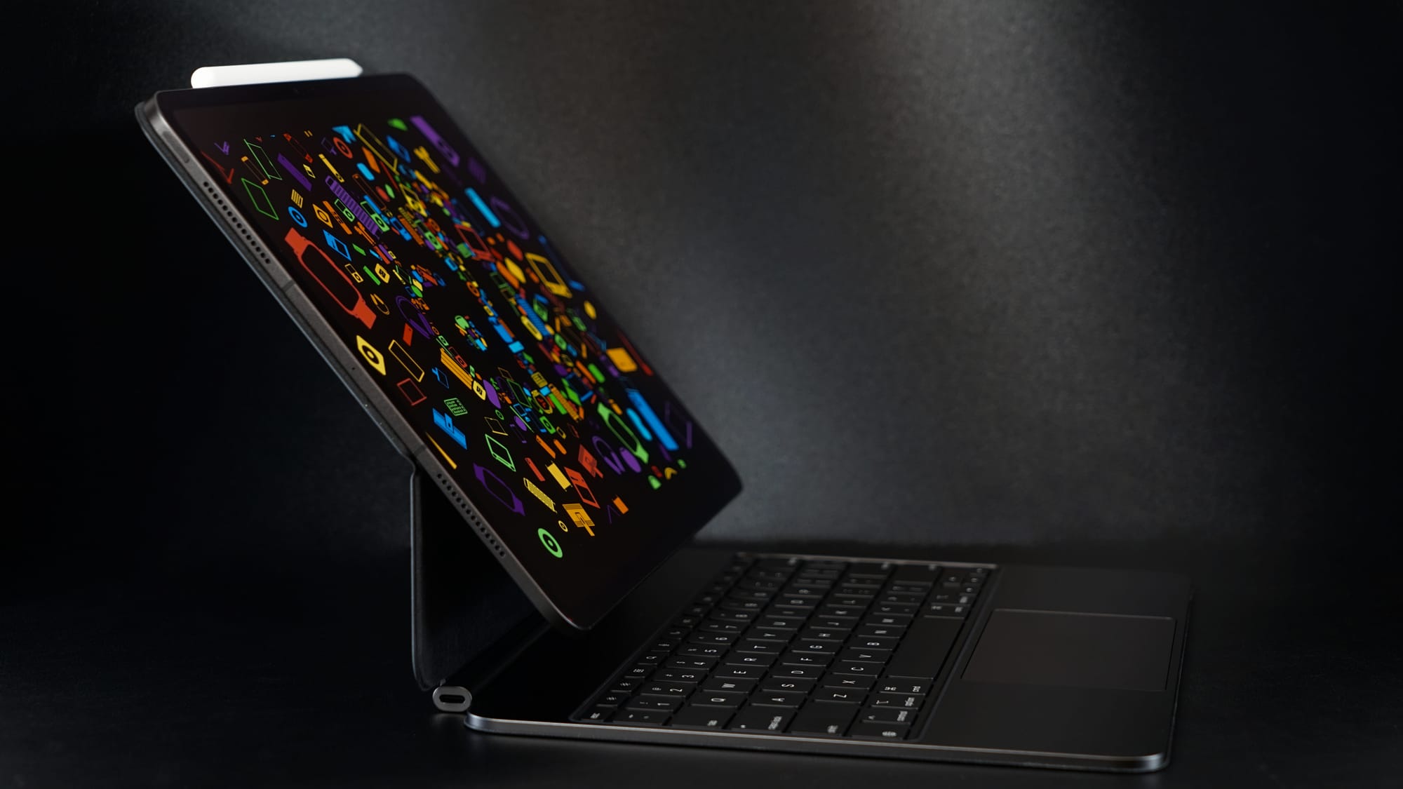 An iPad Pro in a Magic Keyboard with a colorful wallpaper in a dark space
