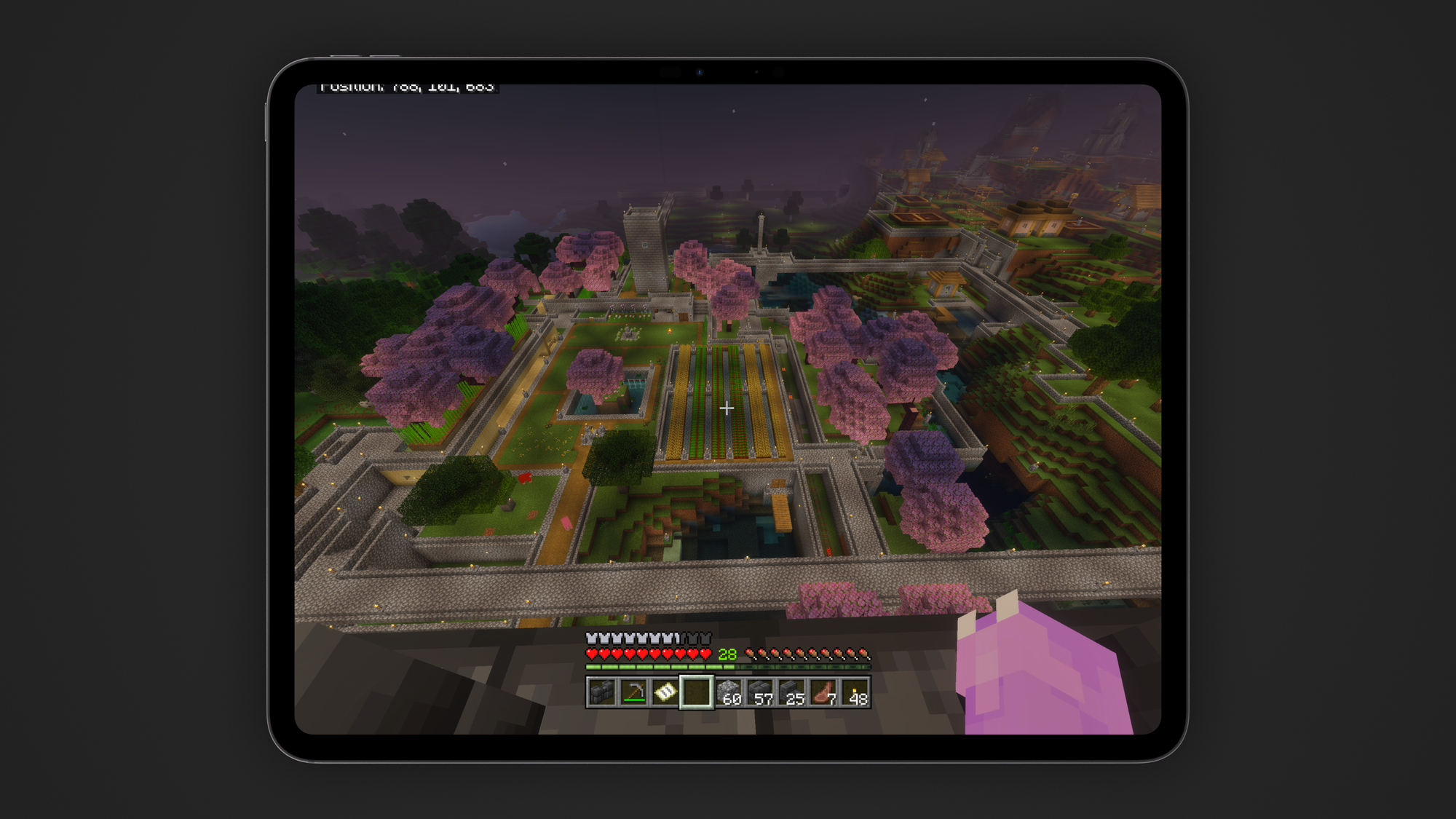 A screenshot of Minecraft shown on an iPad Pro. Cherry trees litter an organized space of stone and grass.
