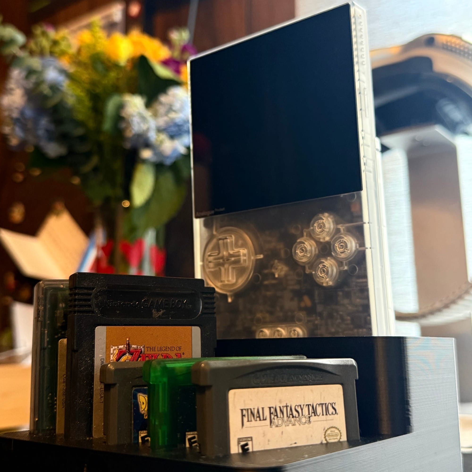 The Analog Pocket in a 3D printed stand, various GameBoy games are on display