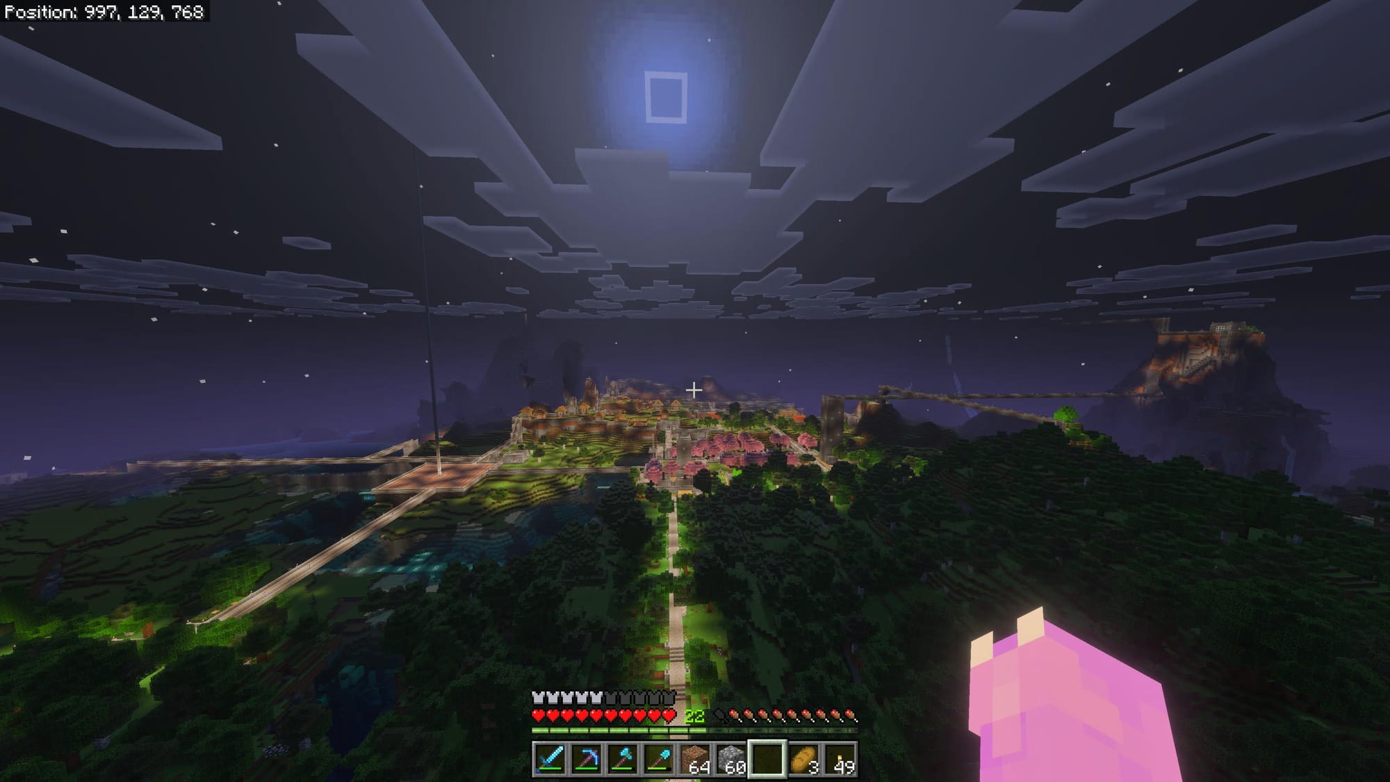 A screenshot of Minecraft overlooking a large array of lit up structures amid trees