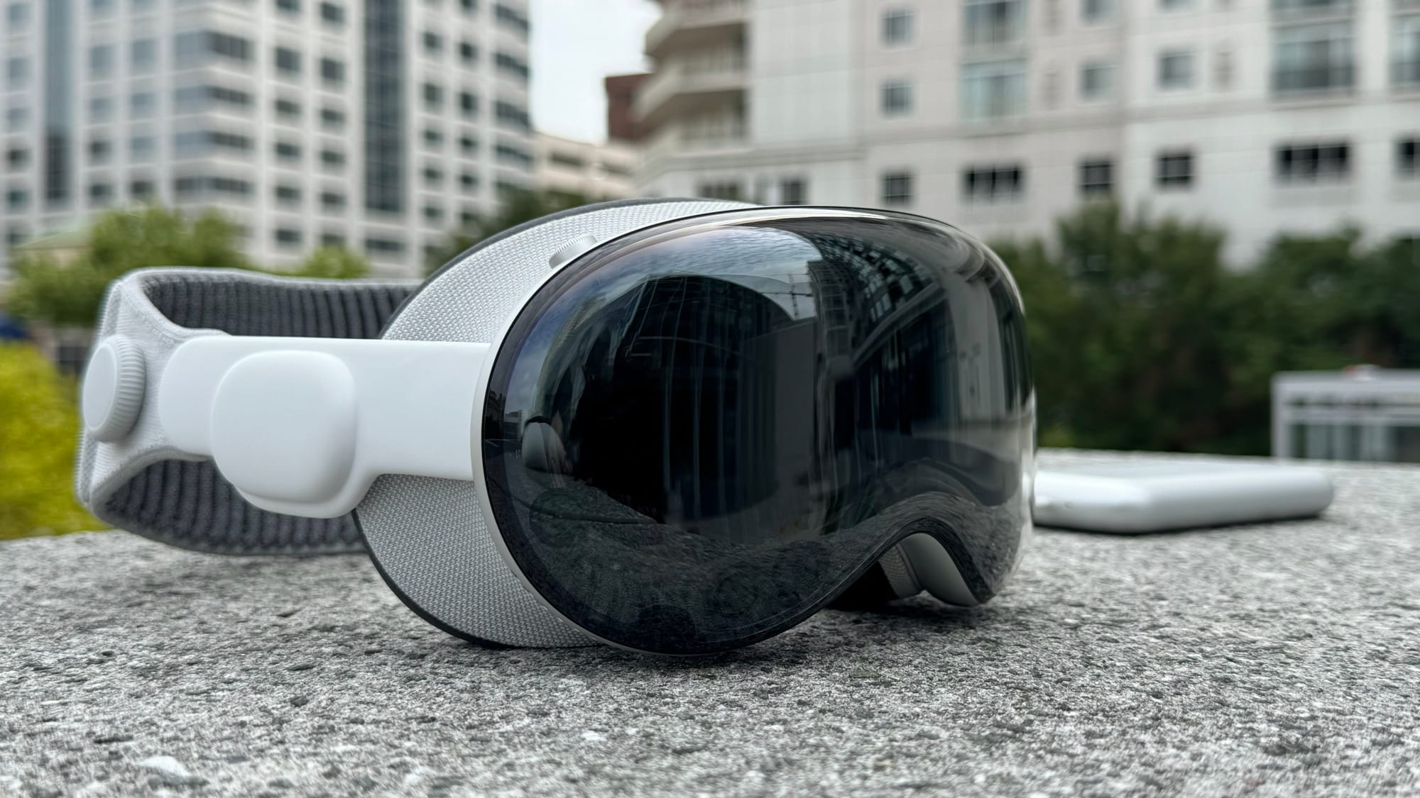 Apple Vision Pro on a stone column with buildings in the background