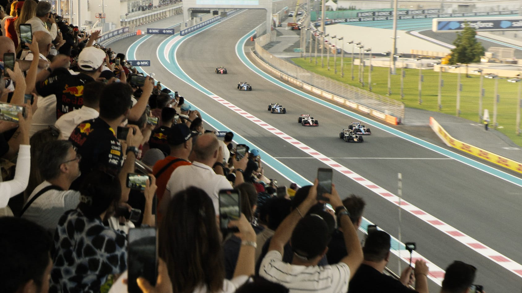 A racing scene in the F1 movie showing the vehicles on a track and a crowd watching from the stands