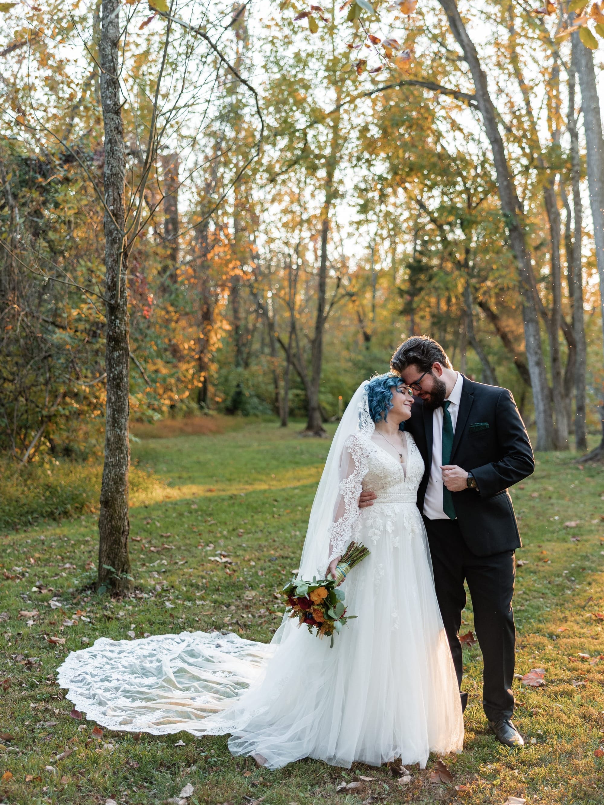 A photo of bride and groom, Wesley and Natalie, standing at sunset in a fall woodland clearing