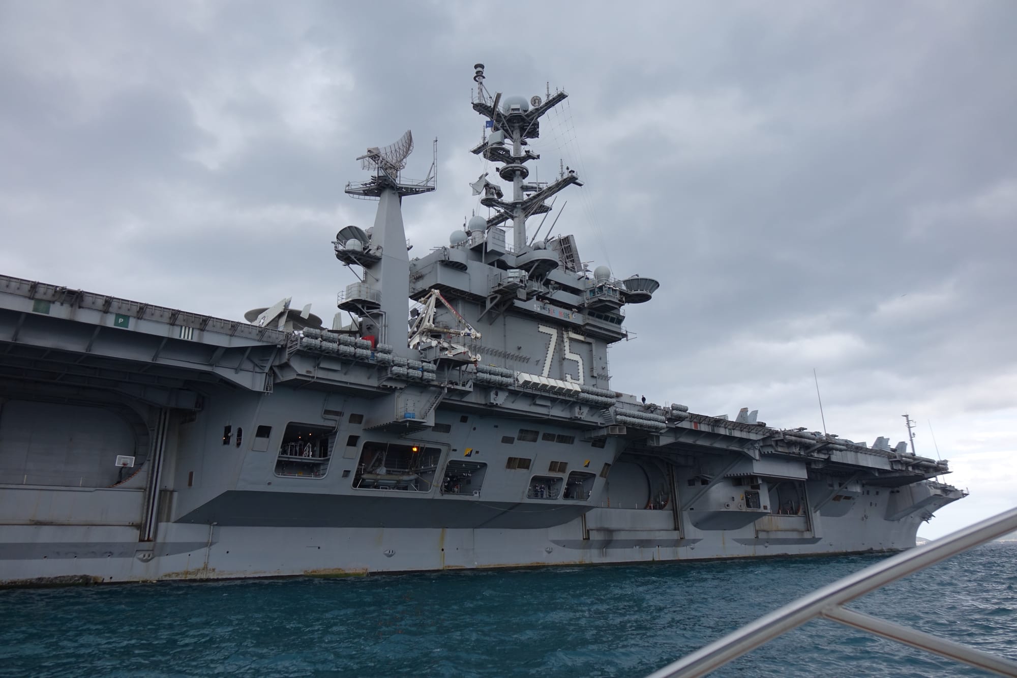 A photo of a carrier in blue water, the number 75 visible on its side