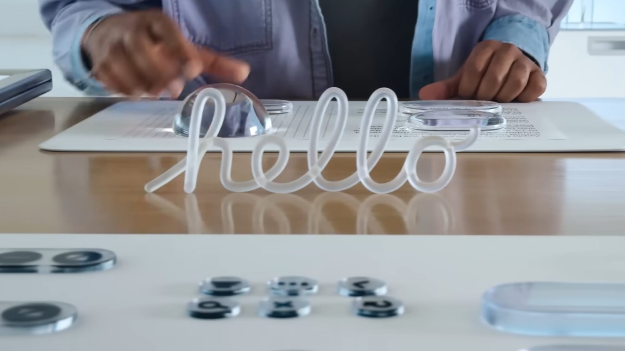 A glass ornament showing "hello" in cursive and glass objects in front of a person on a table