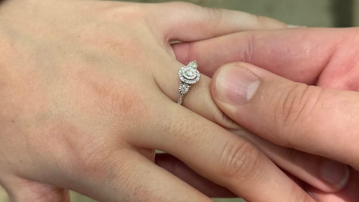 A photo of an engagement ring placed on a finger