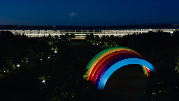 Apple Park at night showing the lit up rainbow stage in the center of the ring building