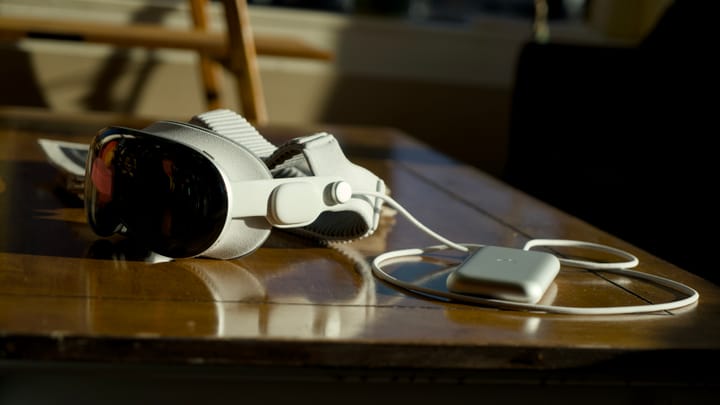 Apple Vision Pro with a dual strap on a table at a coffee shop by its battery pack