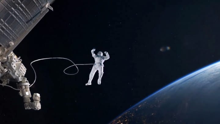 An astronaut tethered to a spacecraft taking a selfie with an iPhone above Earth